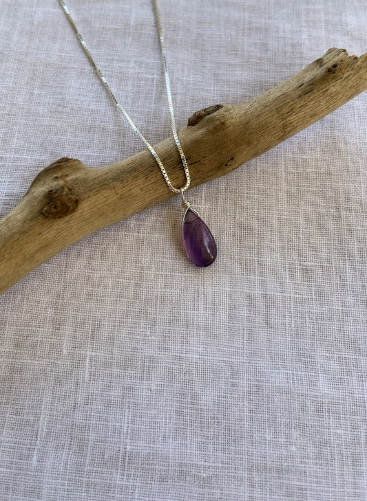 A handcrafted amethyst teardrop necklace featuring a natural violet-colored gemstone on a delicate sterling silver chain