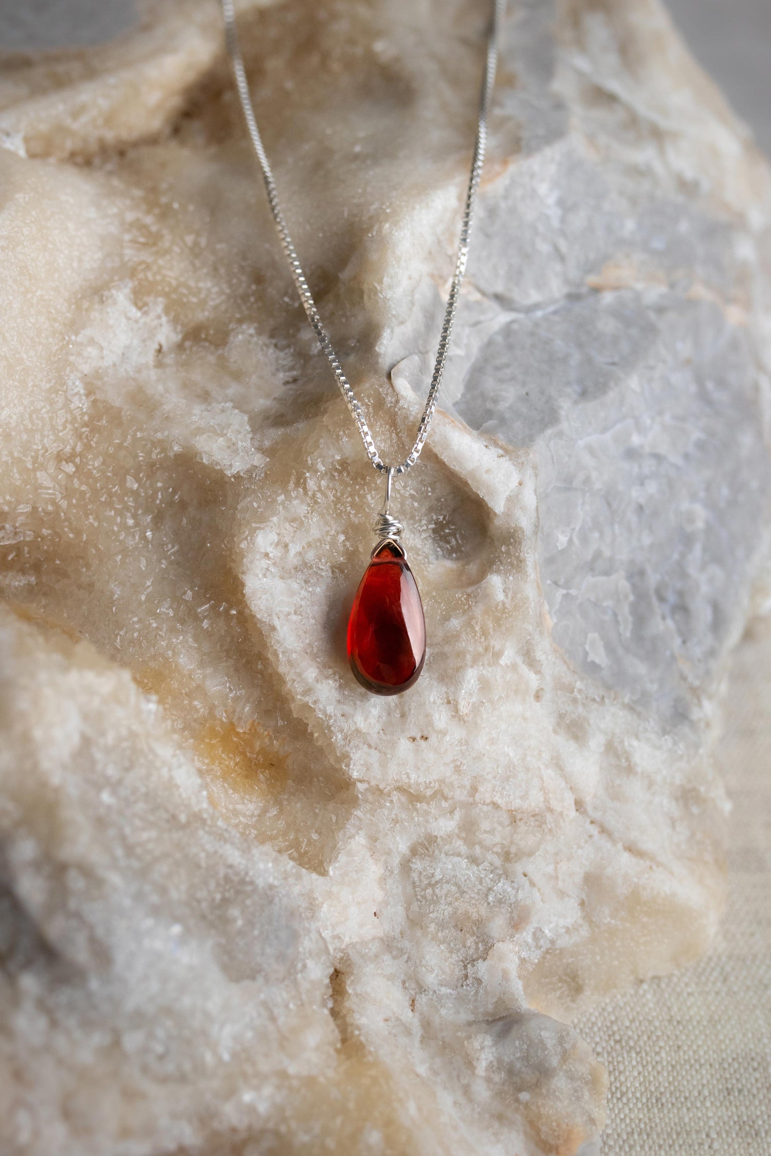 A handcrafted minimalist garnet necklace with a deep red gemstone wire-wrapped on a delicate sterling silver chain.