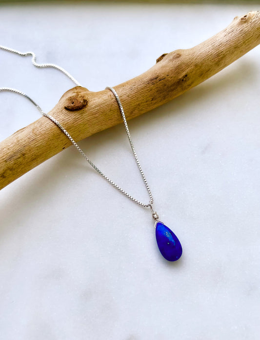 A handcrafted teardrop Lapis Lazuli necklace with a deep blue gemstone, wire-wrapped and hanging from a delicate silver chain.