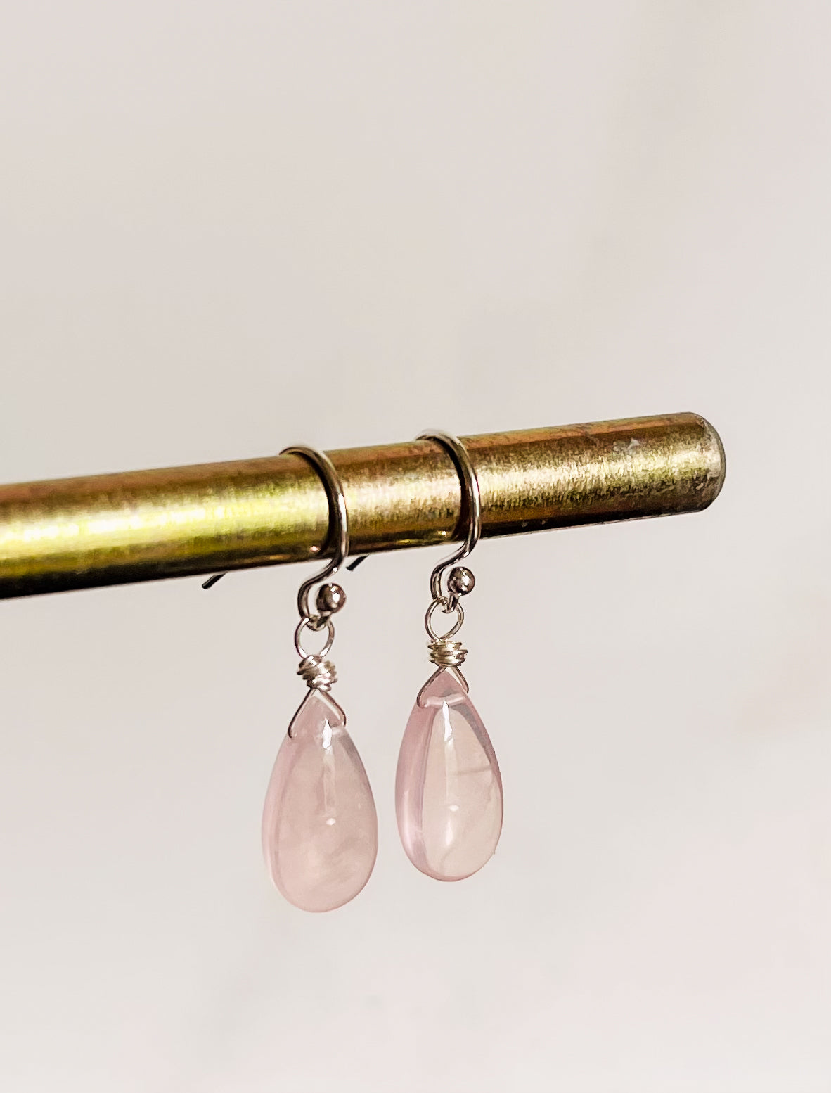 A pair of handcrafted Rose Quartz teardrop earrings with hand-cut pink gemstones hanging from delicate sterling silver French ear wires
