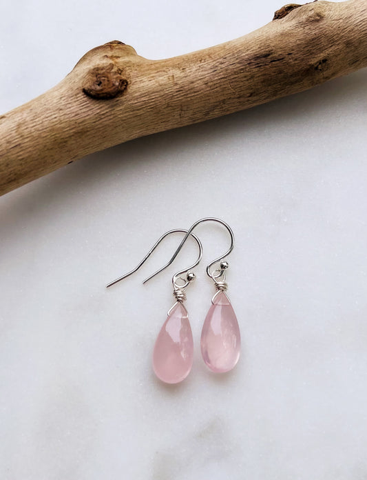 A pair of handcrafted Rose Quartz teardrop earrings with hand-cut pink gemstones hanging from delicate sterling silver French ear wires
