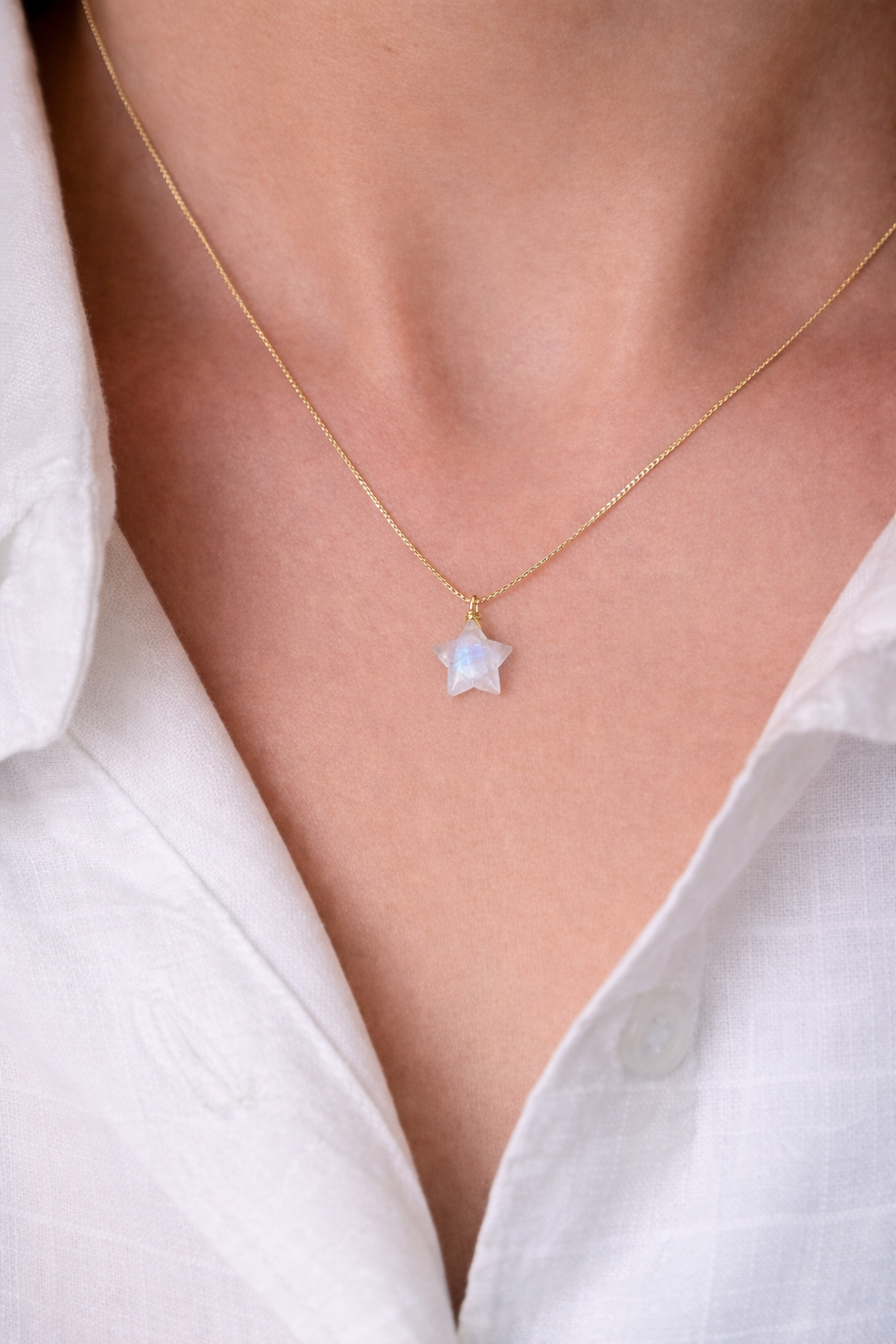 Necklace with a star-shaped pendant worn by a person in a white shirt.