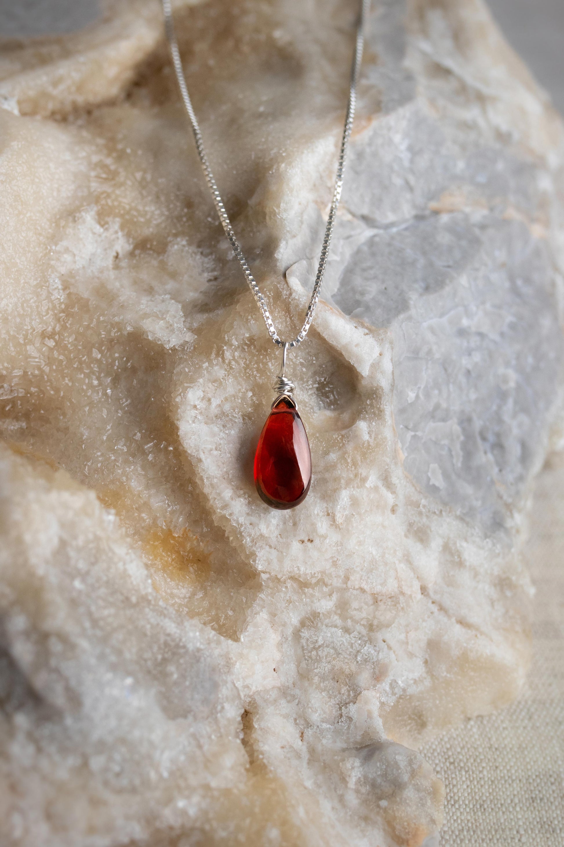 A handcrafted minimalist garnet necklace with a deep red gemstone wire-wrapped on a delicate sterling silver chain.