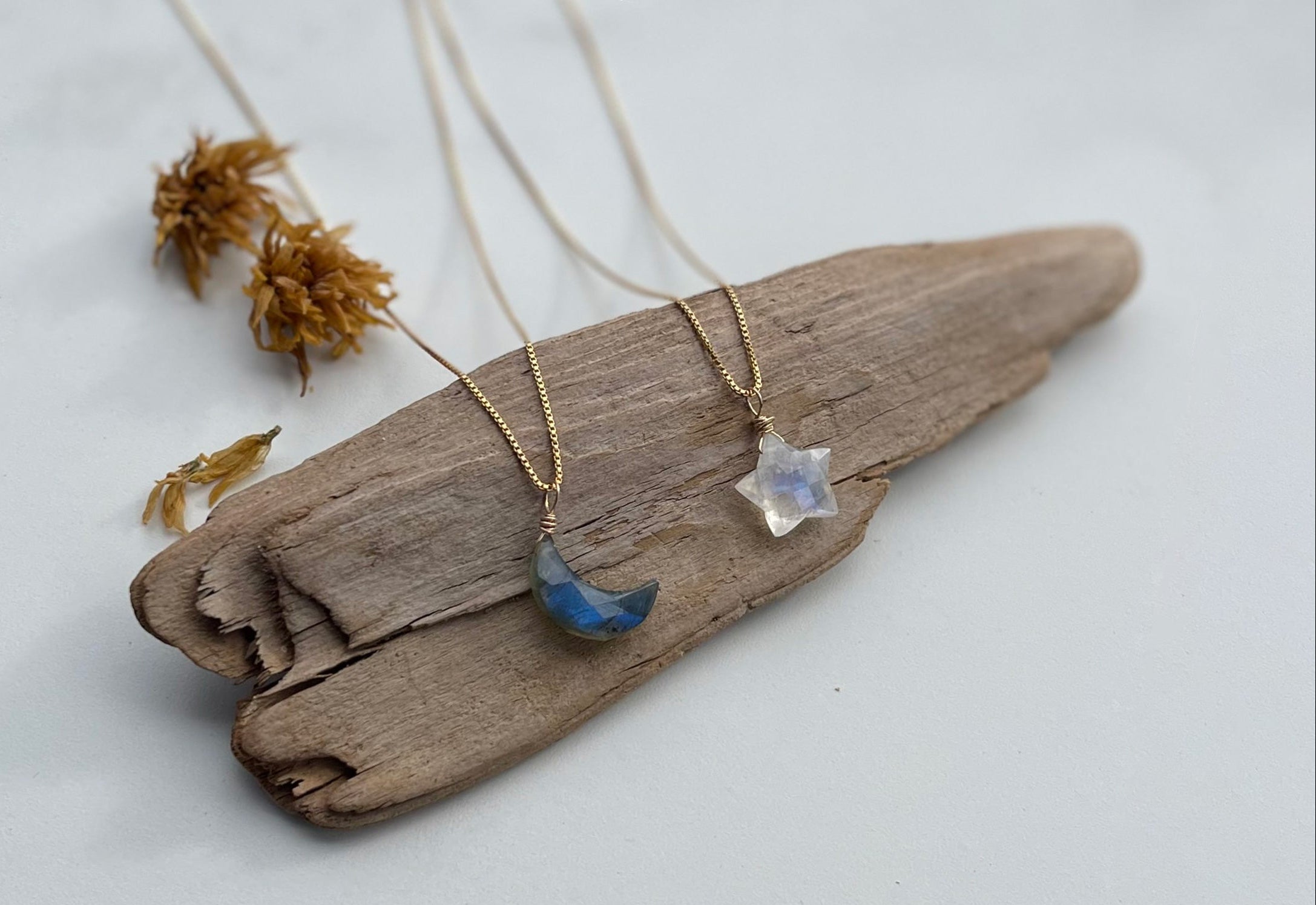 Labradorite Moon + Moonstone Star Necklaces laying on drift wood