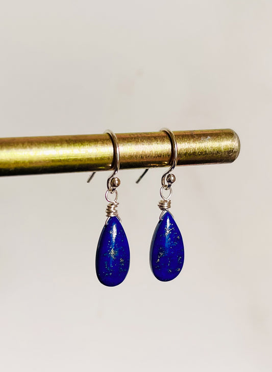 A pair of handcrafted Lapis Lazuli teardrop earrings made with sterling silver French ear wires. The deep blue gemstones show natural golden flecks.