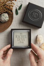 Load image into Gallery viewer, Jewelry box with &#39;Rachel Dunn Jewelry&#39; branding, earrings, and decorative items on a textured surface.
