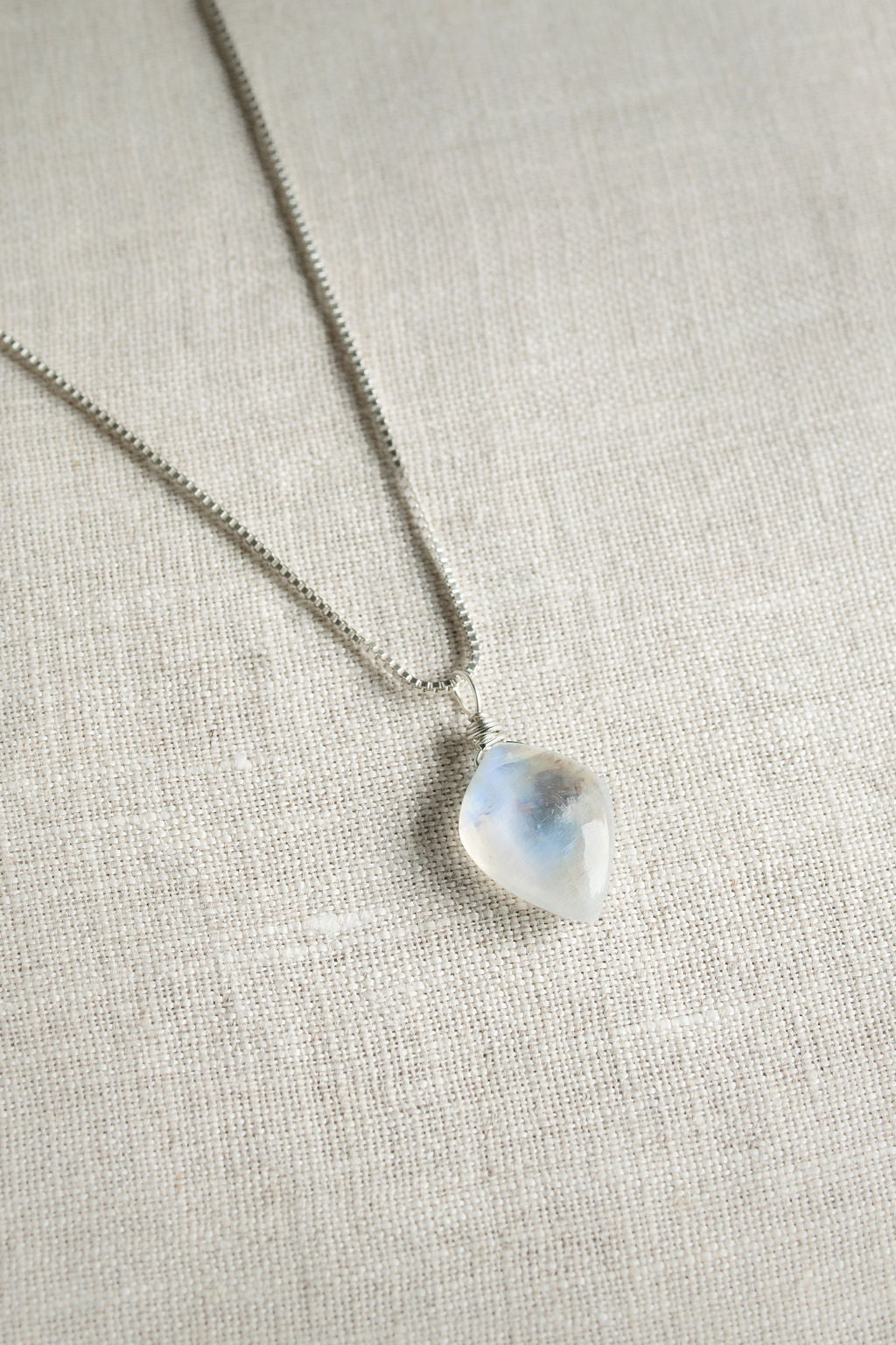 Necklace with a moonstone gemstone pendant on a light fabric background