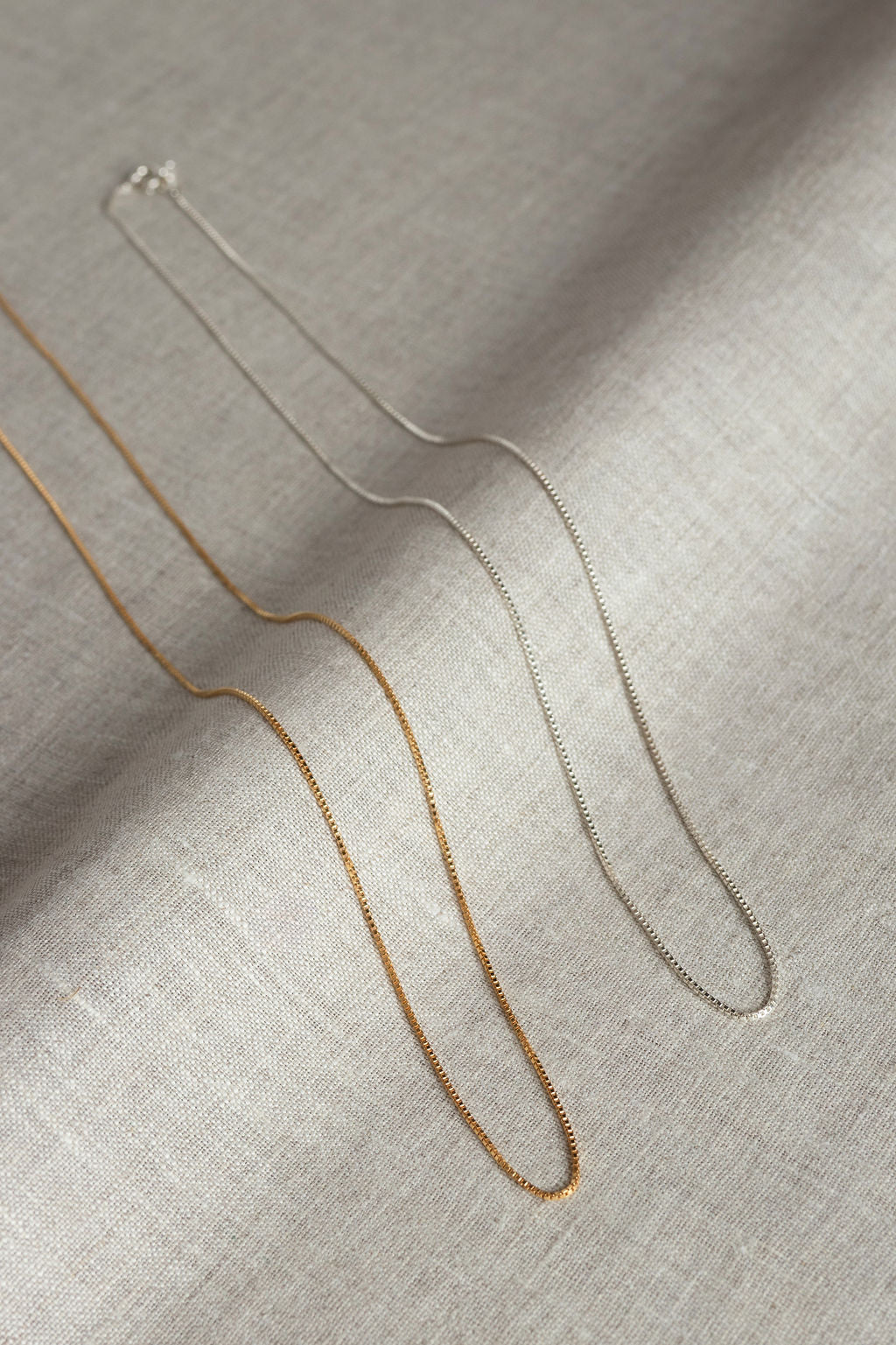 Sterling Silver and Gold Chain laying on linen fabric
