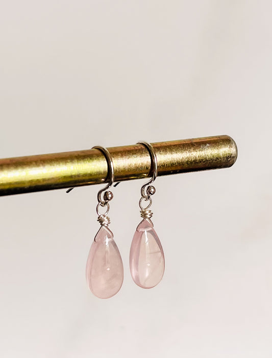 A pair of handcrafted Rose Quartz teardrop earrings with hand-cut pink gemstones hanging from delicate sterling silver French ear wires